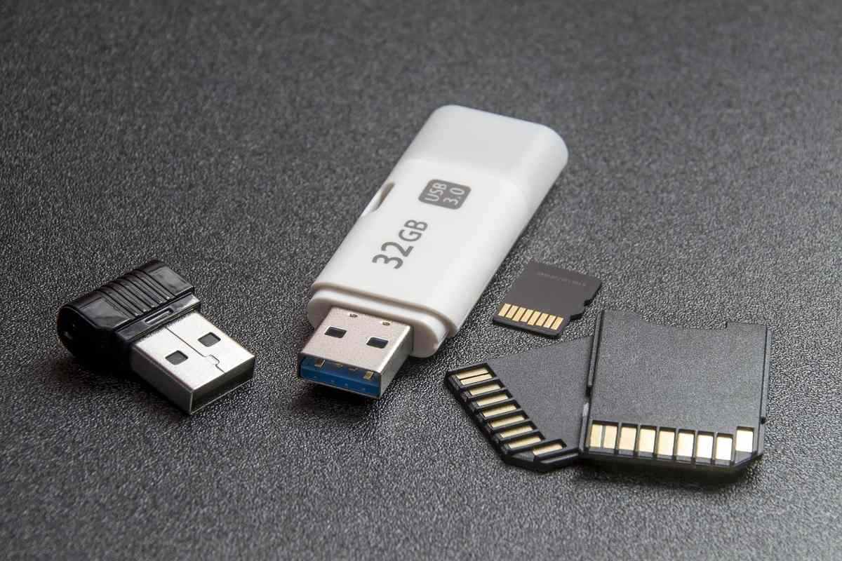 Clé USB blanche et cartes mémoire avec connecteurs dorés sur surface grise Clé USB blanche et cartes mémoire avec connecteurs dorés sur surface grise